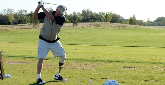 A disabled Veteran takes a swing at a golf ball on a golf course