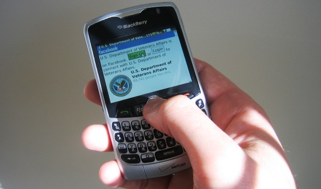 Person's hand holding a Blackberry set to VA's Facebook page