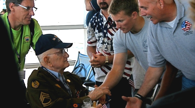 Picture of men shaking the hand of a Veteran in a Wheel chair