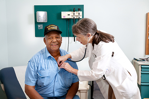 Image of a Veteran getting a check up from a female VA doctor