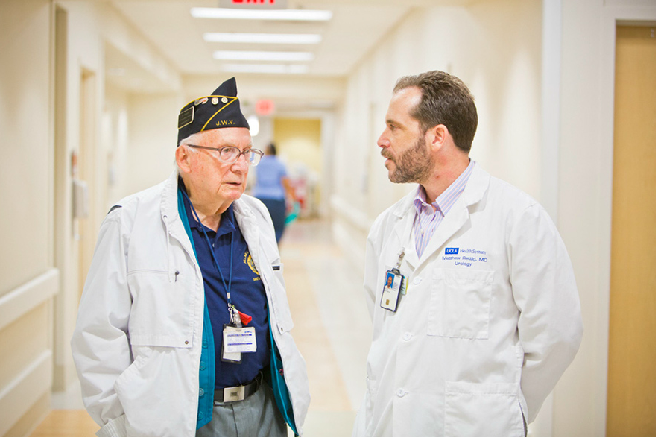 A doctor speaking to an older veterans in a VA hospital.