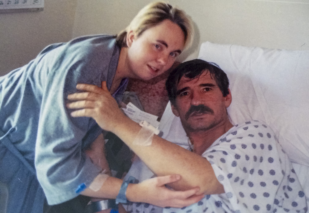 Elise Brown standing next to Roy Jeffers who is laying in a hospital bed