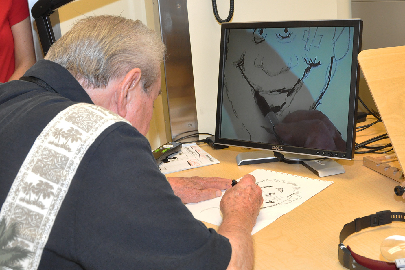 A man paints in front of a computer monitor.