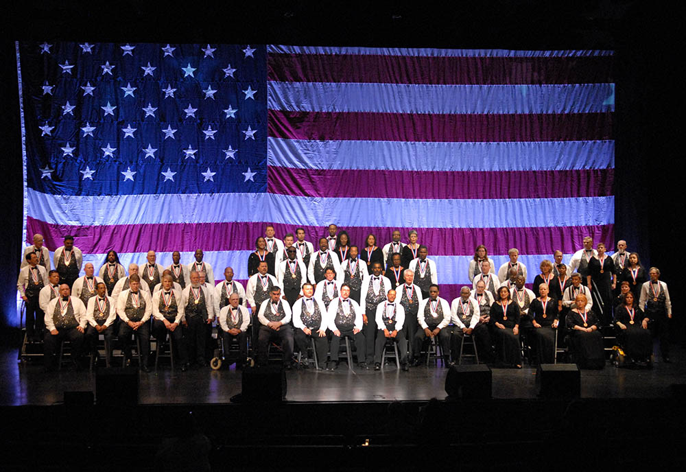 A choir sits in front of the American flag