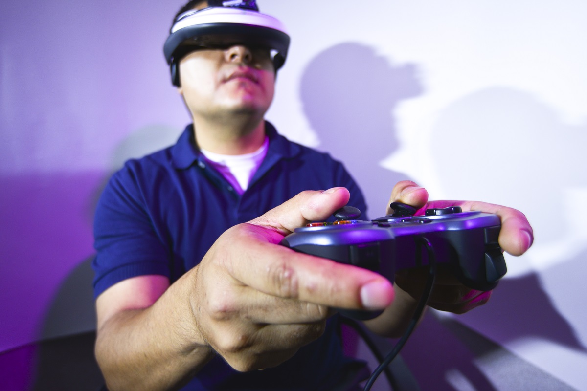 A man wearing a VR visor holds a gaming controller.