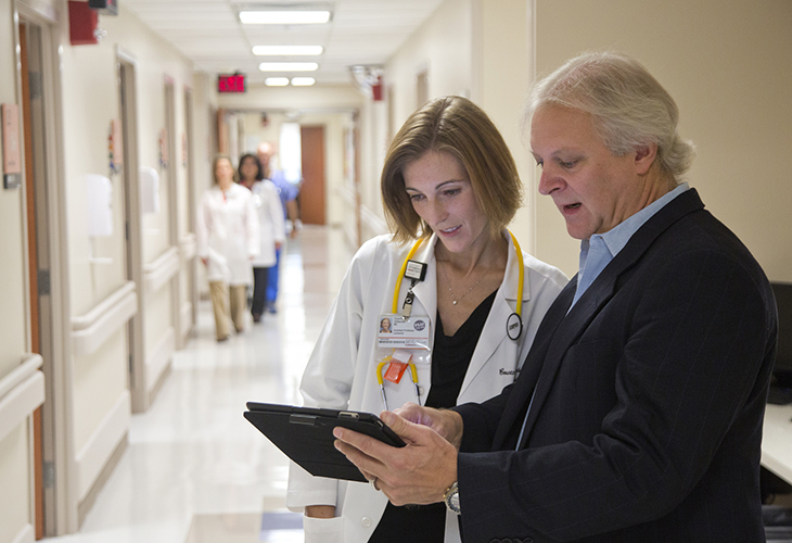 Image of a Female doctor and man in a suit reviewing medical chart in cancer hospital