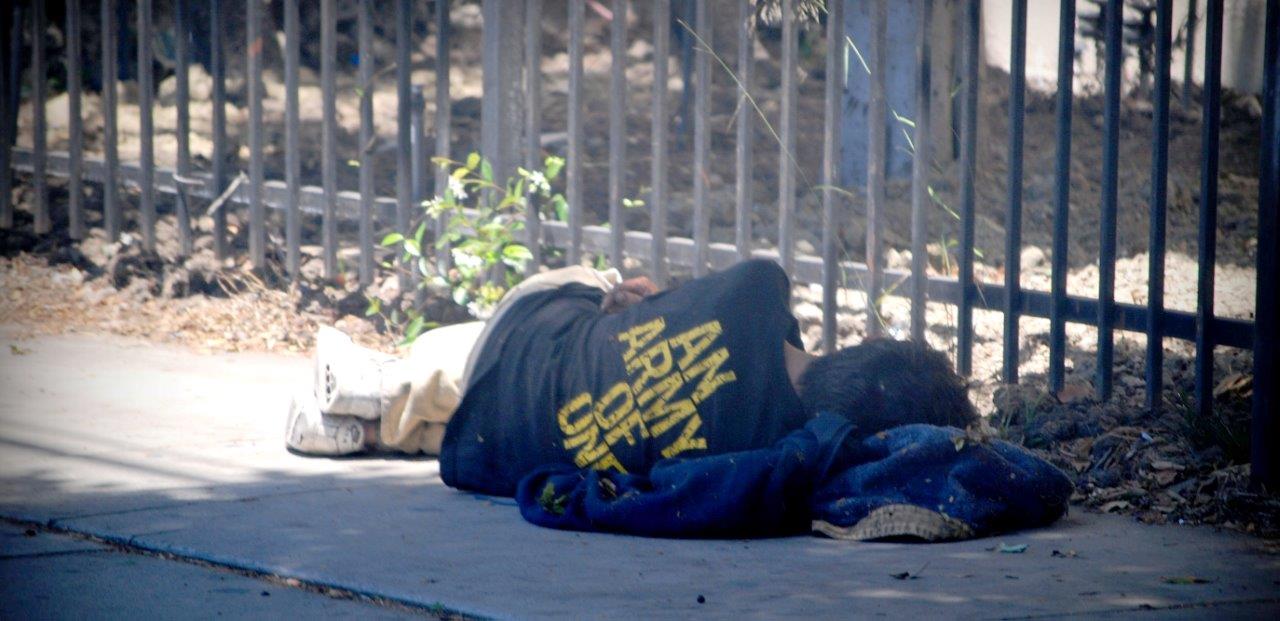 Image of a homeless man sleeping on the street.