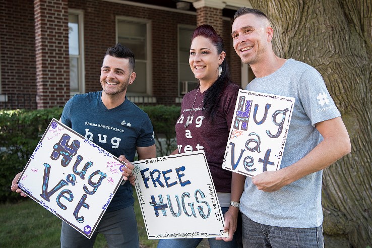 Three Veterans Posing with 'Hug a Vet' Sign
