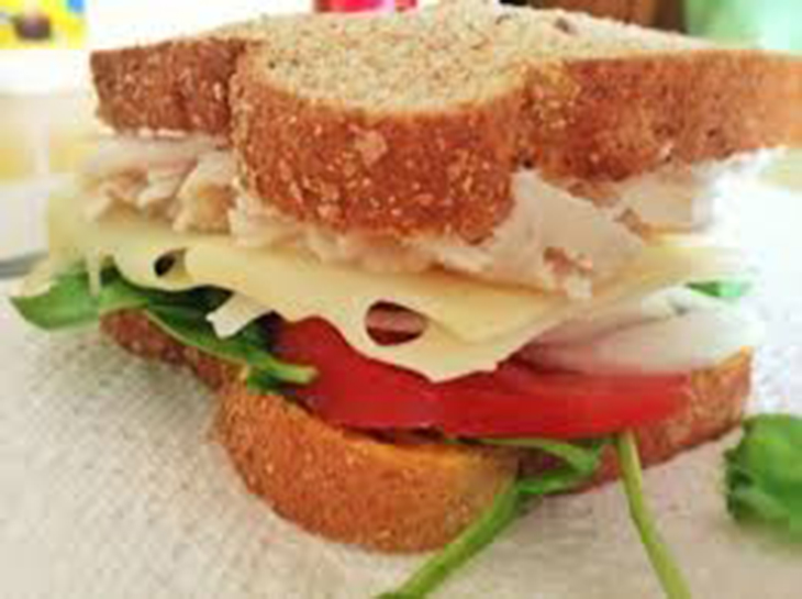 image of a sandich with swiss cheese, lettuce and tomato.