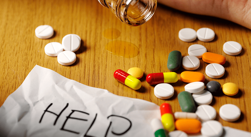 Pills rest on a table with the word Help on a piece of paper