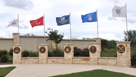 picture of entrance to Fort Same Houston National Cemetery, resting place of Carlos G. Martinez--flagfs of armed services flying over entrance