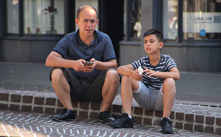 image of a man and boy sitting on a curb