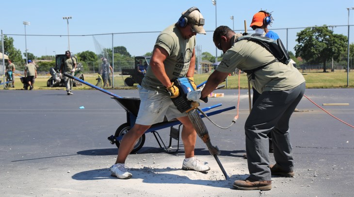 image veterans using a jackhammer to make repairs to an outdoor basketball court