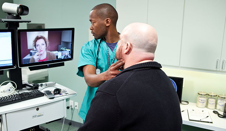 image of a health technician, a vetaan patient and a doctor appearing remotely via computer / video..