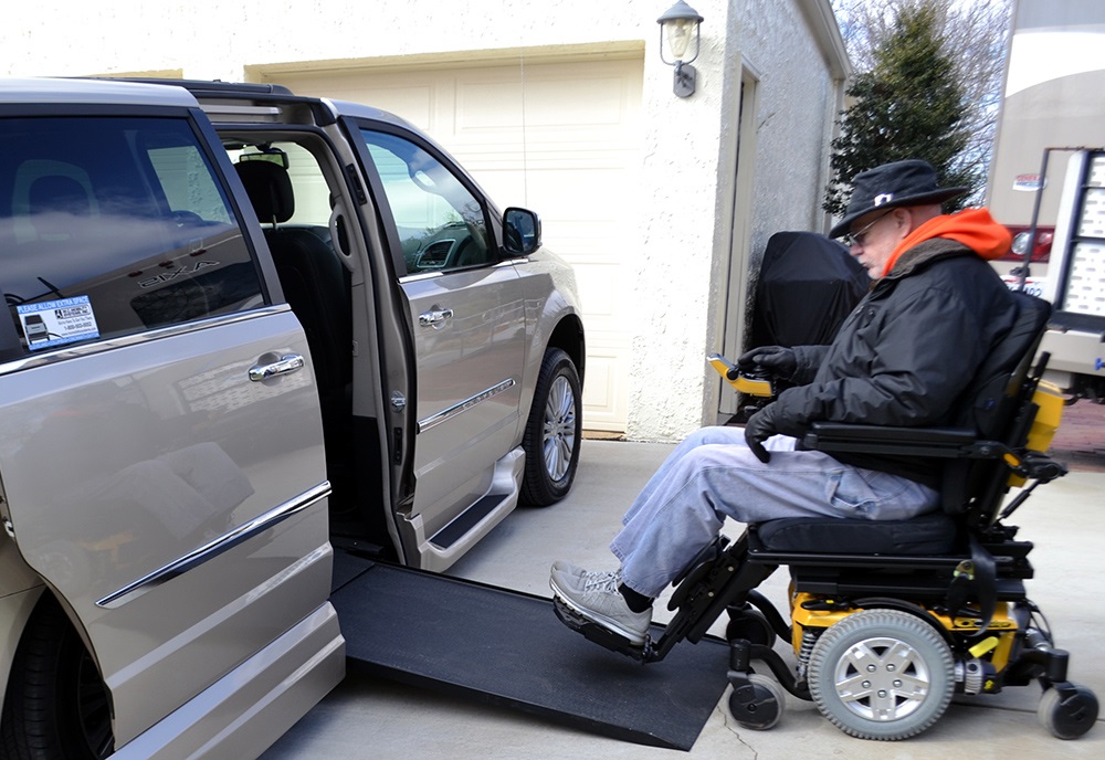 An elderly male Veteran in a wheelchair, entering a van.