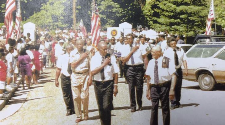 Image of people marching in a parade in the mid 70s.