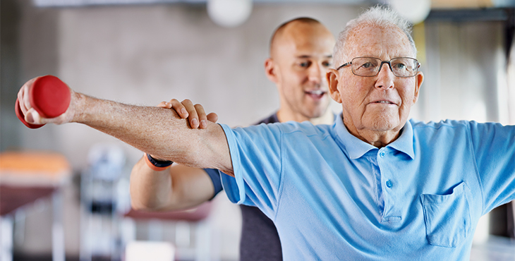 Image of a physiotherapist helping a senior man with weights