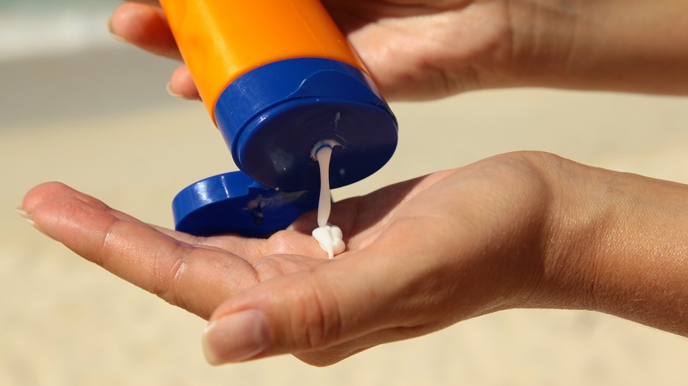 woman holding and applying suntan lotion on a beach