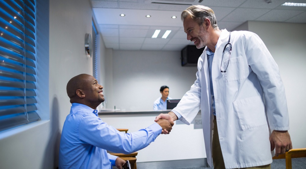 Male doctor shaking hands with patient in hospital