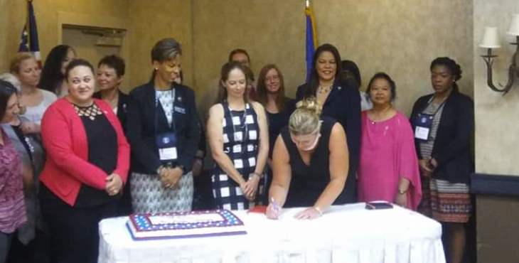 Image: Group of women behind a table observing the signing of the agreement.