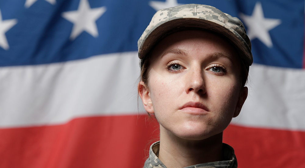 Female solider standing in front of American Flag