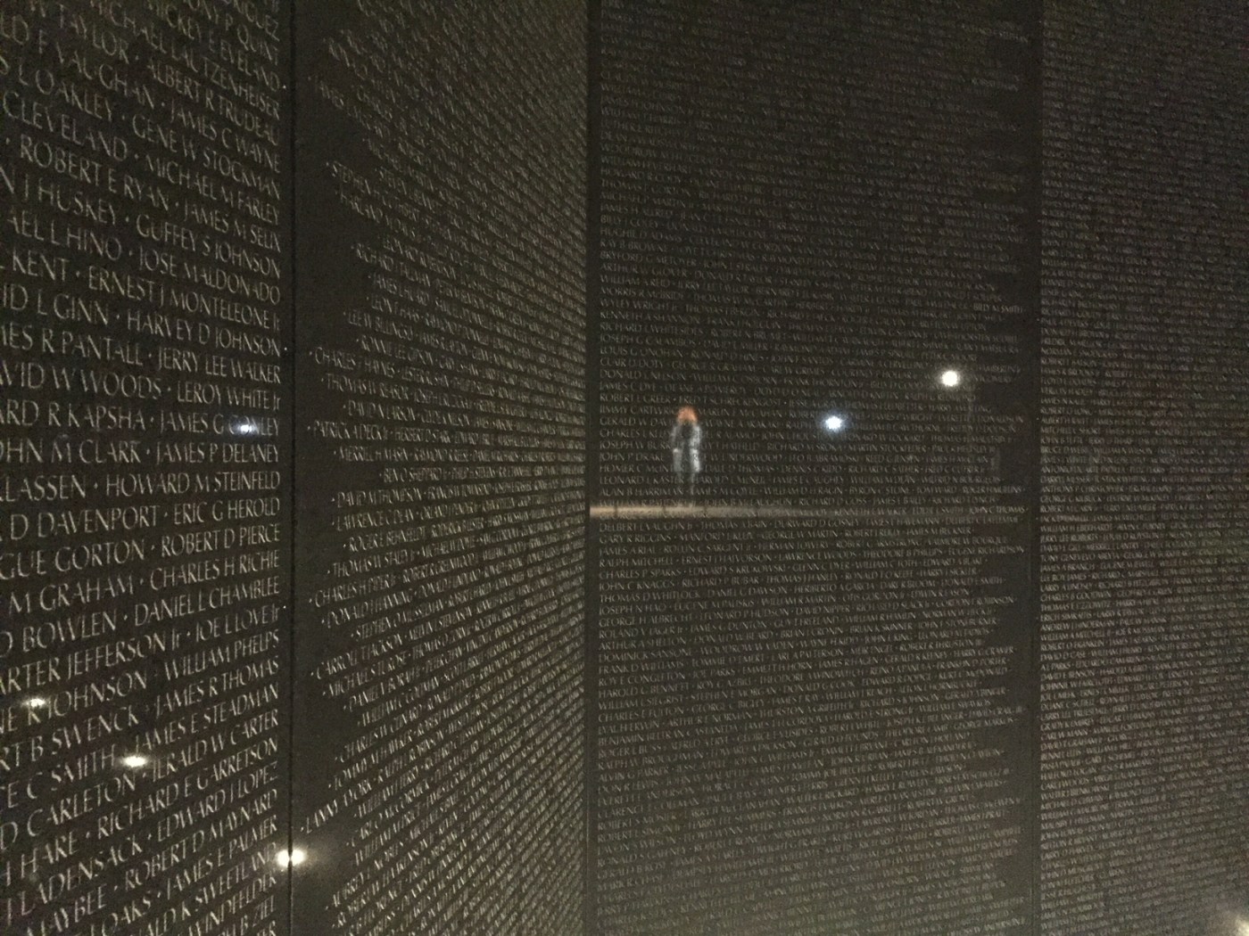 Reflection of woman reading names on the wall