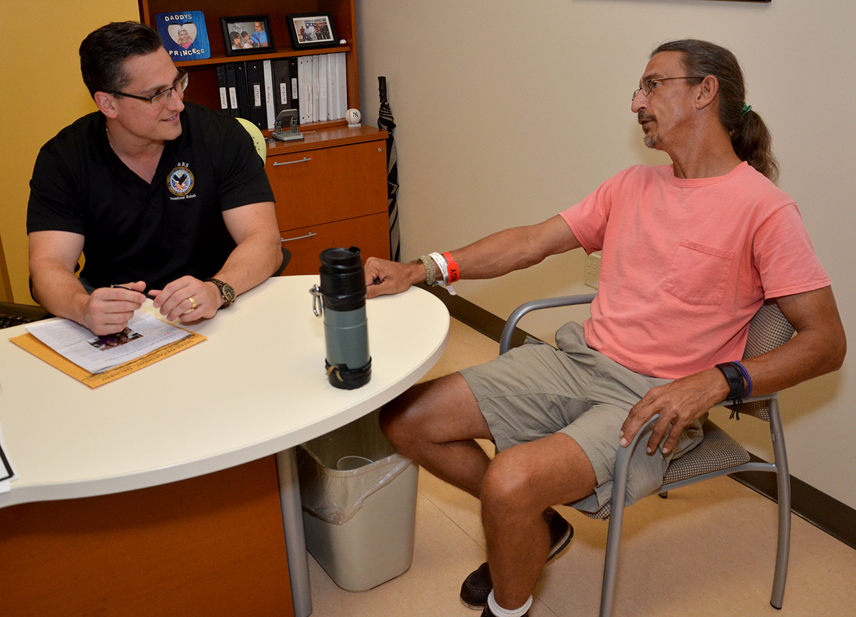Tampa VA vocational rehabilitation specialist Todd Goldin talks with Army Veteran Patrick Stamm during the Veteran's recent reevaluation at the hospital. By coincidence, Goldin's mother, Judie Pink-Goldin, was one of Stamm's original occupational therapists after a four-story fall caused massive injuries and brought him to Haley in 1996 for recovery and rehabilitation.