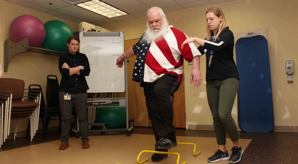 Army Veteran Gary Lucas navigates a hurdle exercise with the help of study coordinator Lydia Paden.
