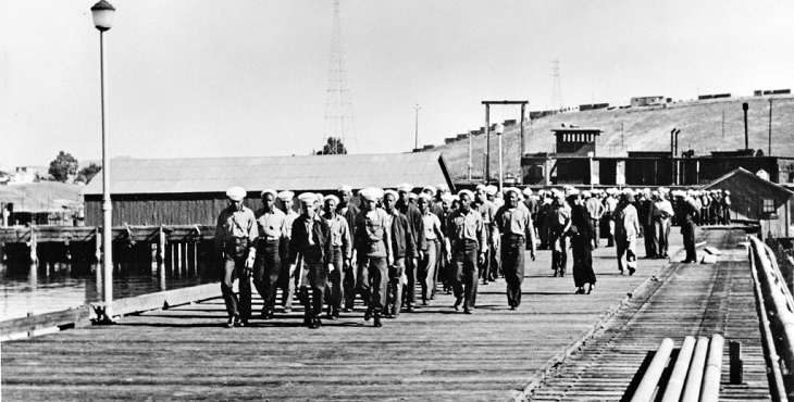 Black and white period photograph of sailors marching in formation on a dock at Port Chicago