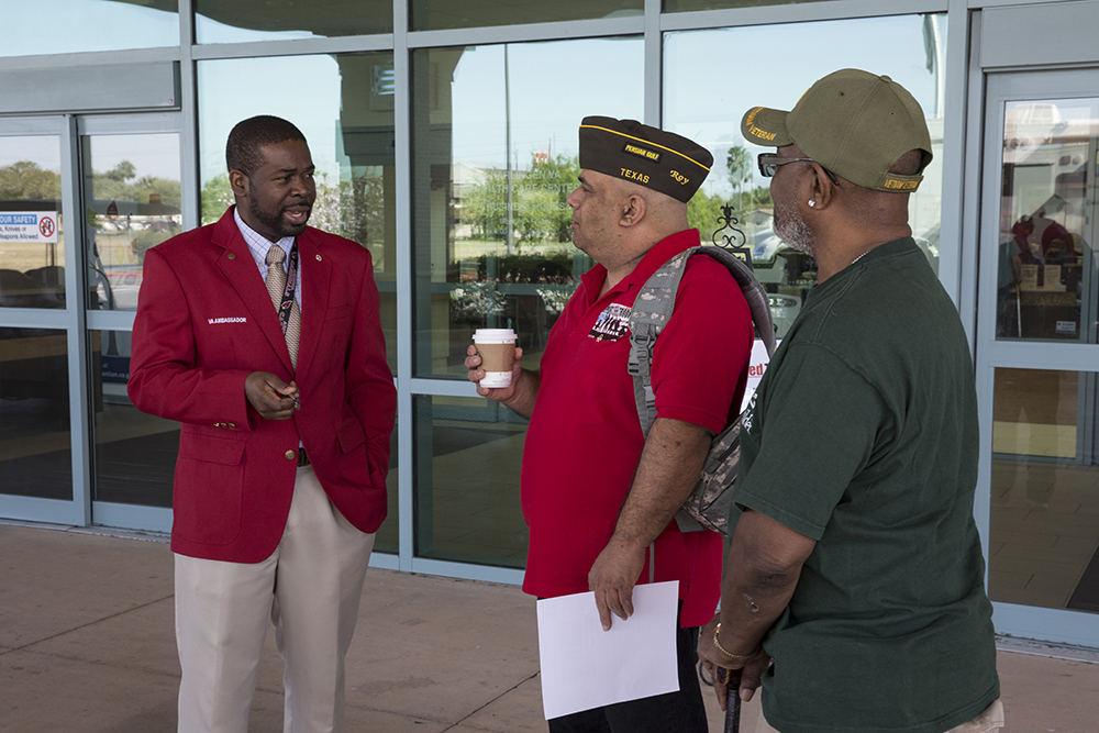 VA Red Coat Ambassador Fabian Cauldwell speaks with Army Veterans Roy Maggard and Fred Patton, who stopped by the VA Health Care Center at Harlingen, Texas on March 20, 2018.