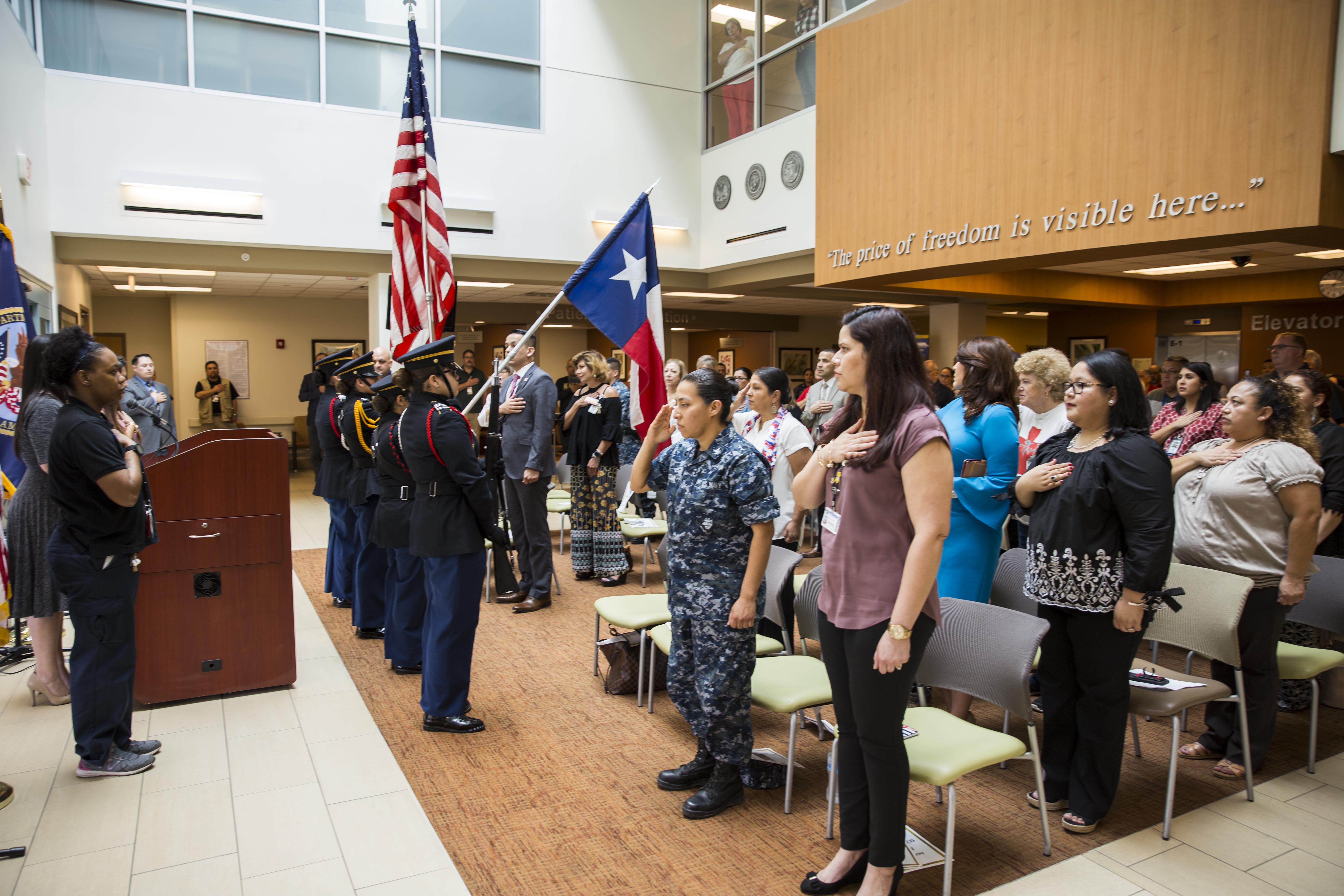 Guests rise to their feet with render salutes and hands over their chest as the Harlingen High School All-Female Army Junior ROTC Color Guard present the colors, while the "Star Spangled Banner" is sung by Mrs. Rebecca Arismendi, during the VA Texas Valley Coastal Bend Health Care System's ceremony in observance of national Women's History Month, which took place March 2, 2018, at the VA Health Care Center at Harlingen, Texas.