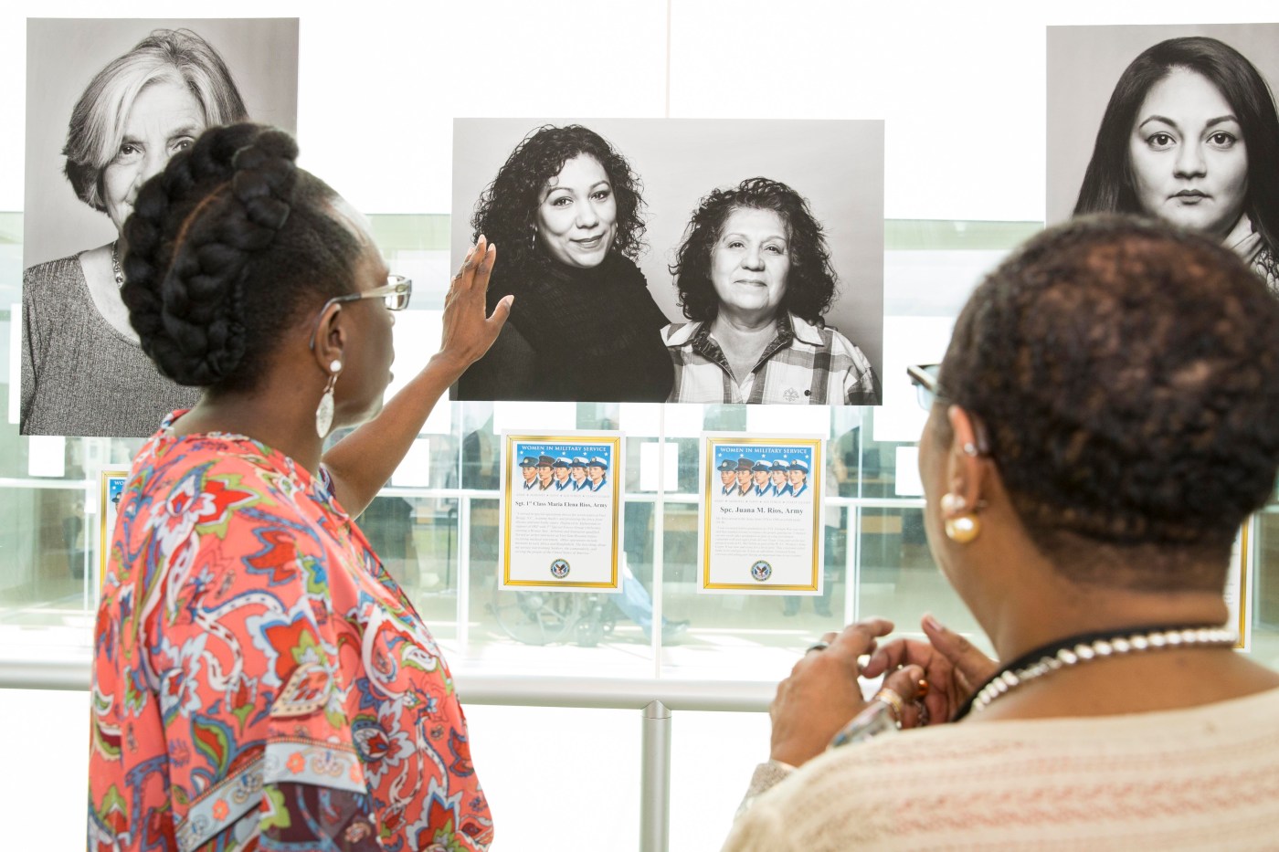 Guests admire and discuss one of the 28 portraits on display as part of the photo exhibit