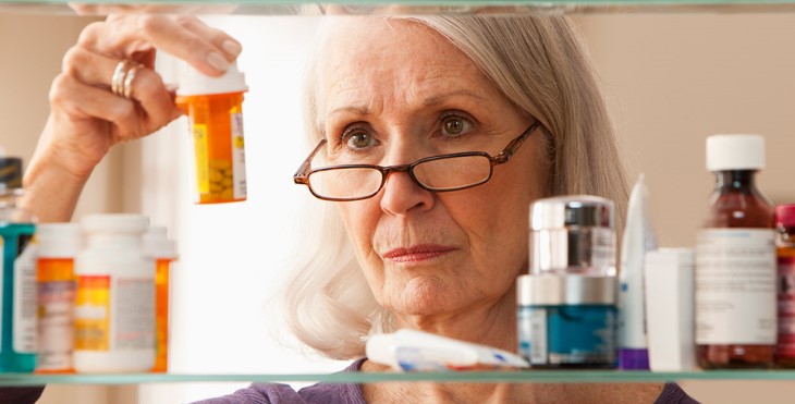 Image: Lady looking at prescription drugs in a medicine cabinet.