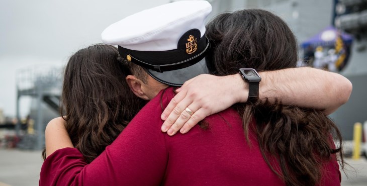 IMAGE: Family hugging a sailor.