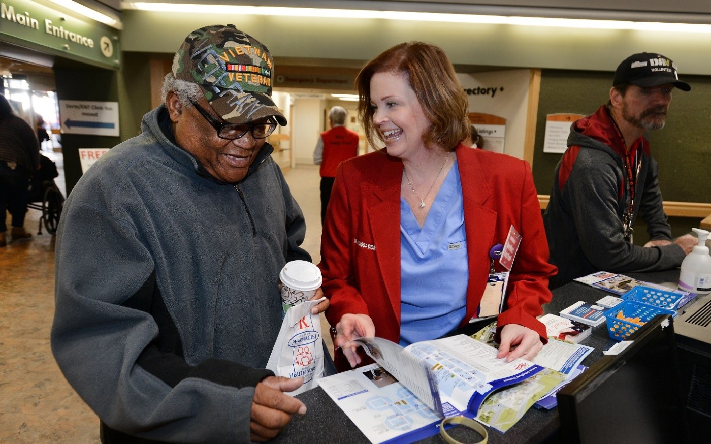Veteran Albert Summons gets help from Central Arkansas VA Red Coat Ambassador Kim Womack, a surgical nurse. (photo by Jeff Bowen.)