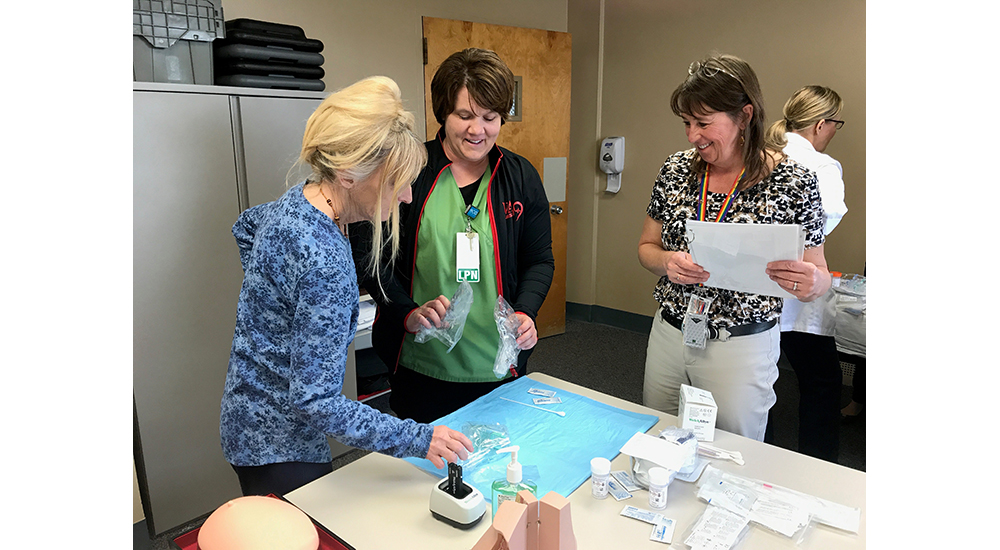Patty Axtell, RN, and Suzanne Rainforth, LPN, practice pelvic exam supply set-up with instructor Jonna Brenton, RN, at Grand Island VAMC