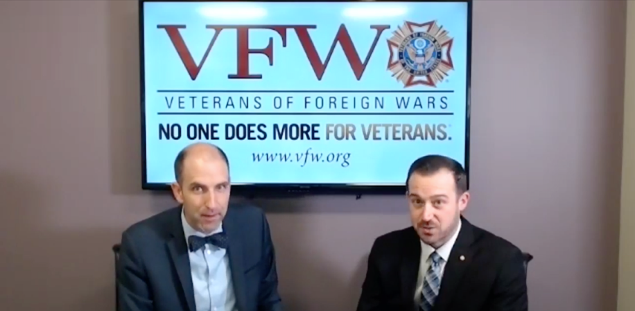 Two men looking at a camera with a TV Screen on the wall in the background. Text reads: VFW - Veterans of Foreign Wars - NO ONE DOES MORE FOR VETERANS. - www.vfw.org