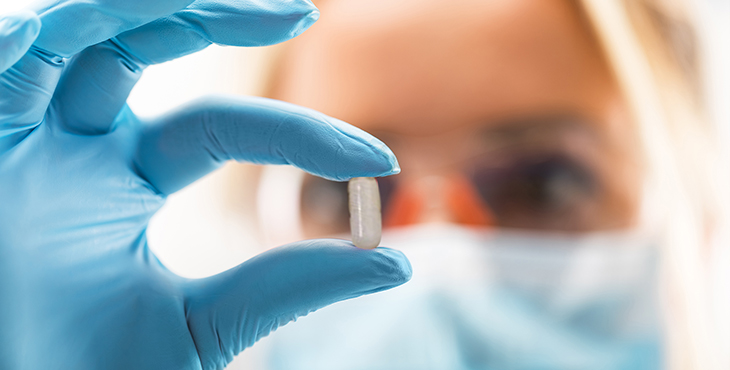 stock photo of researcher holding white capsule