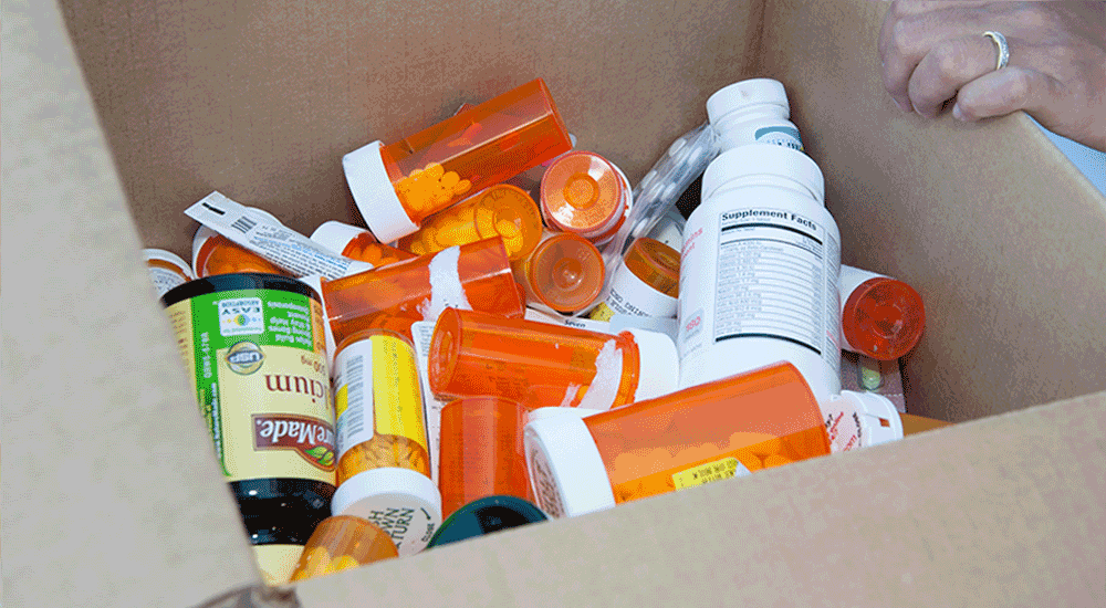 Cardboard box full of medication bottles of different sizes and shapes