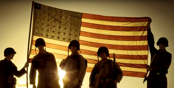 Picture shows multiple servicemembers in uniform silhouetted against the an American flag in the background.