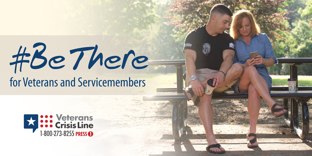 Picture shows two people sitting at an outdoor table looking at a phone. Text reads: #BeThere for Veterans and Servicemembers - Veterans Crisis Line 1-800-273-8255 - PRESS 1