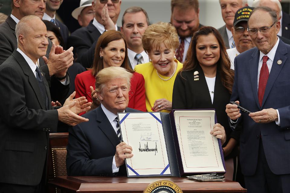 Picture shows president Donald Trump holding up a signed copy of the MISSION Act