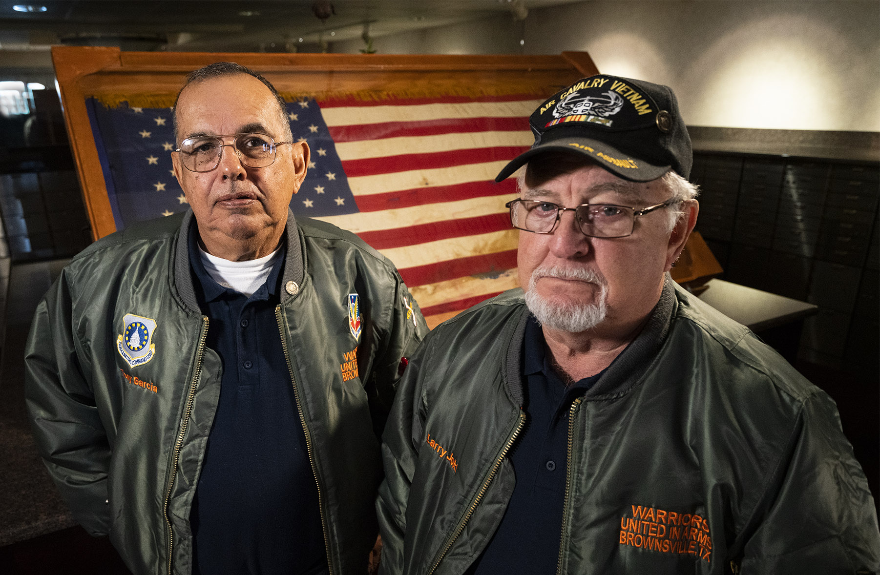 PORTRAIT of Tony Garcia and Larry Jokl in front of the ceremonial flag