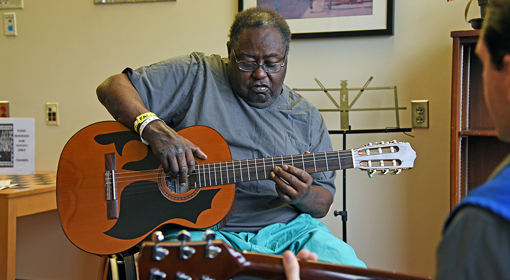 A man learning to play the guitar