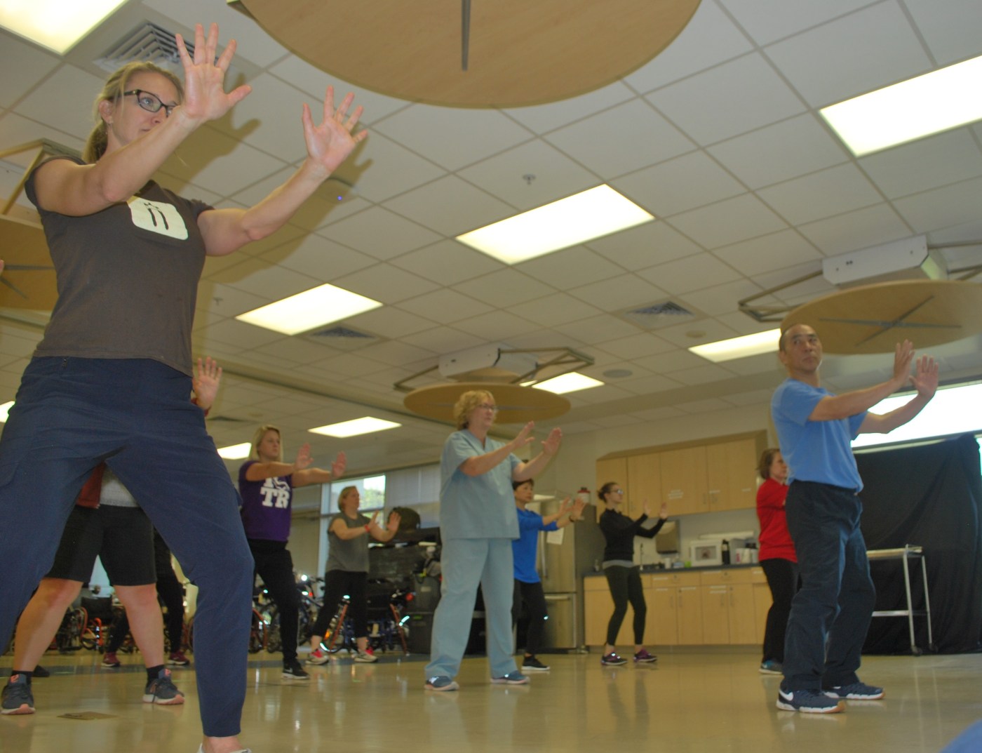 VA workers and patients in tai chi, mid pose.