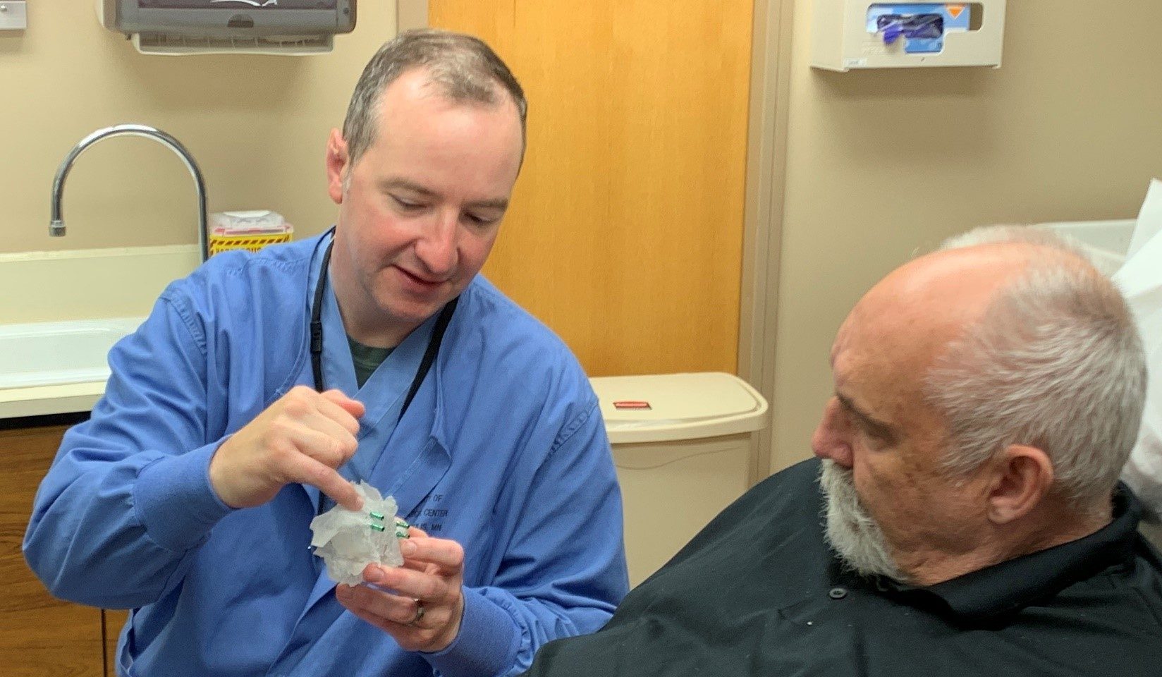 A dentist shows a male patient a 3D model of his planned surgery