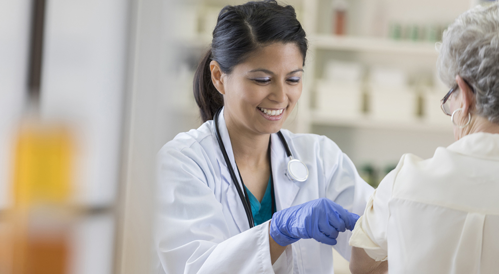 A nurse prepares a lady’s arm for a flu immunization injection during flu season