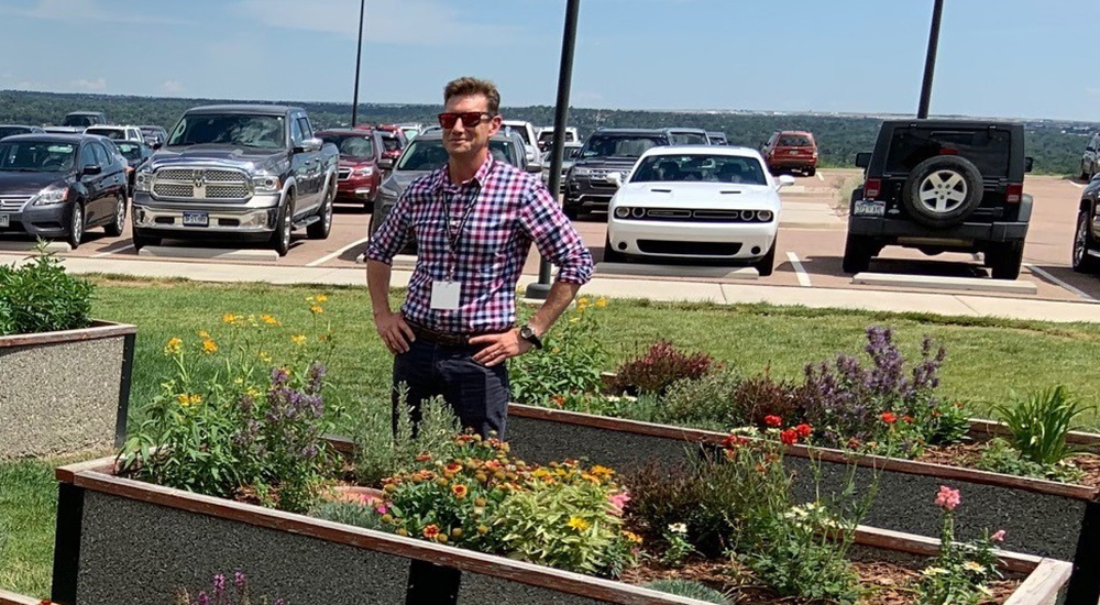 A man standing next to raised planting beds planted with flowers