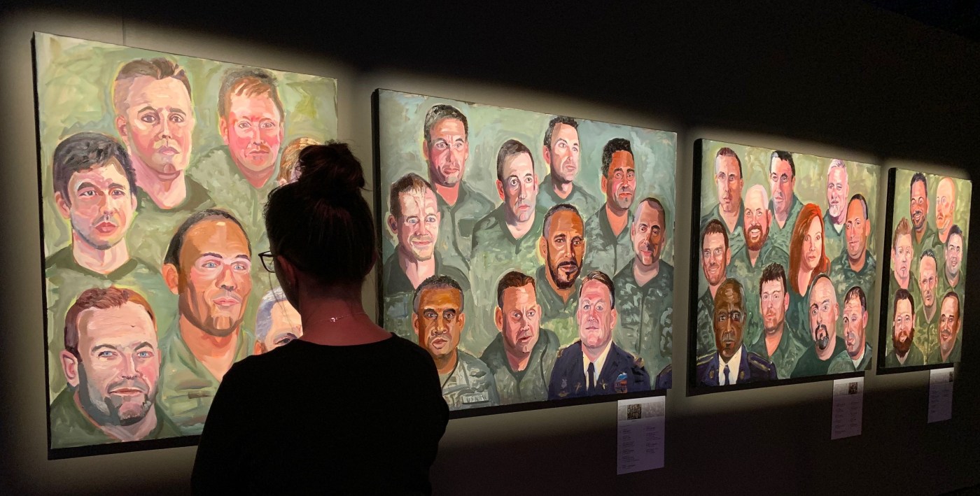 Patron looks at Portraits of Courage paintings