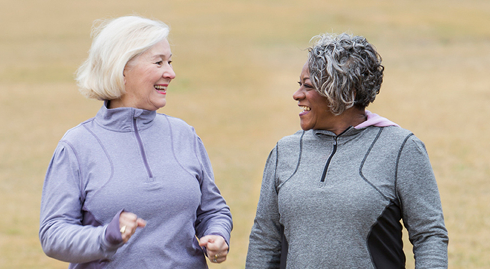 Two women wearing workout gear, smiling and talking